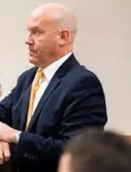 A man in a suit sits in court.