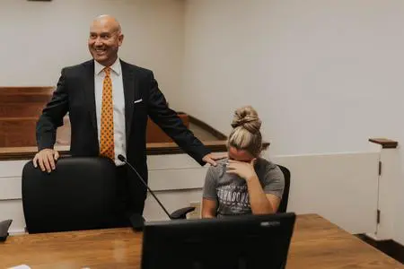 Man in suit comforting woman in courtroom.