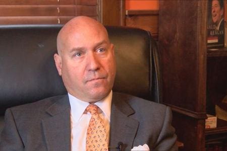 Man in suit and tie sitting in chair.