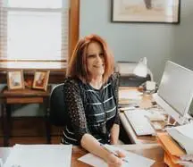 Woman sitting at desk writing in office.