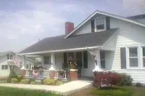 White house with porch and American flags.