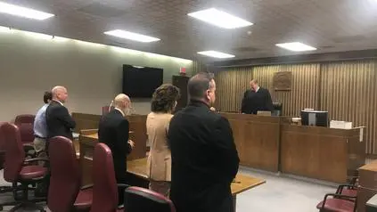 People in a courtroom with a judge.