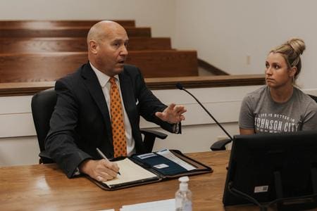 Man in suit signing documents with woman.